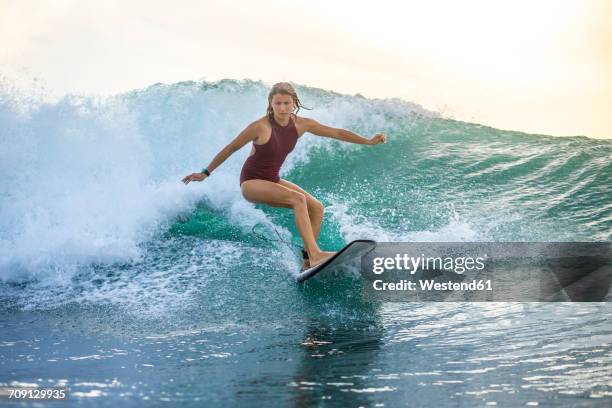 indonesia, bali, woman surfing on a wave - windsurfbrett stock-fotos und bilder