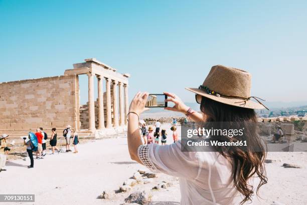 greece, athens, woman taking a cell phone picture of the erechtheion temple in the acropolis - tourismus stock-fotos und bilder