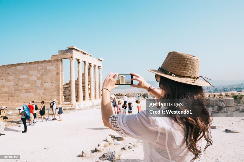 Greece, Athens, woman taking a cell phone picture of the Erechtheion temple in the Acropolis