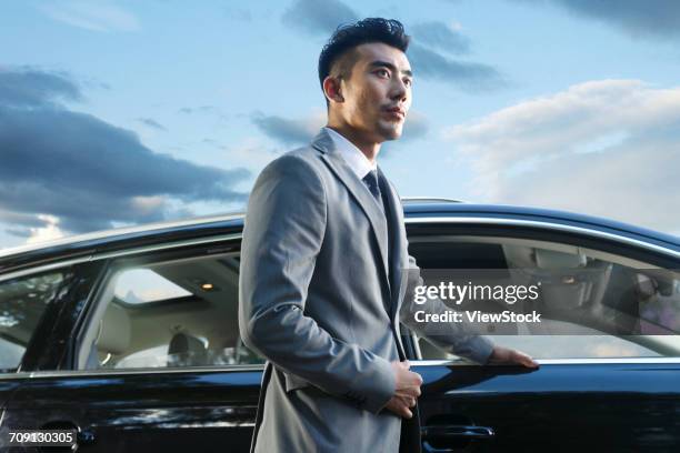 young man standing by car - business man car stock-fotos und bilder