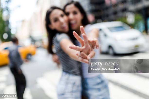 usa, new york city, two young women in manhattan having fun - victory sign stock-fotos und bilder