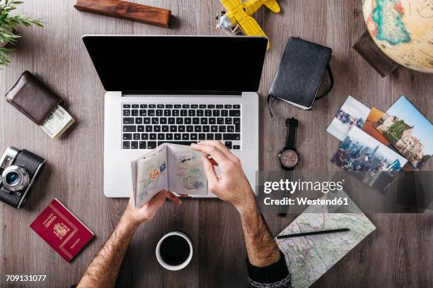 overhead view of man's hand holding passport and travel items on table - vacation planning stock pictures, royalty-free photos & images