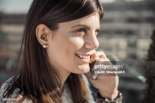 smiling young woman with hearing aid on the phone - ear close up women stockfoto's en -beelden