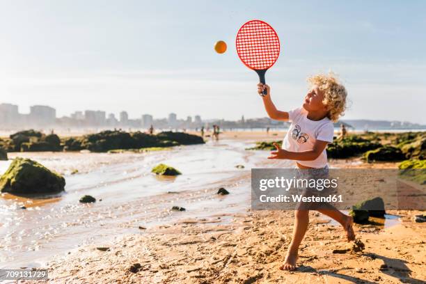 little boy playing beach paddles on the beach - raqueta fotografías e imágenes de stock