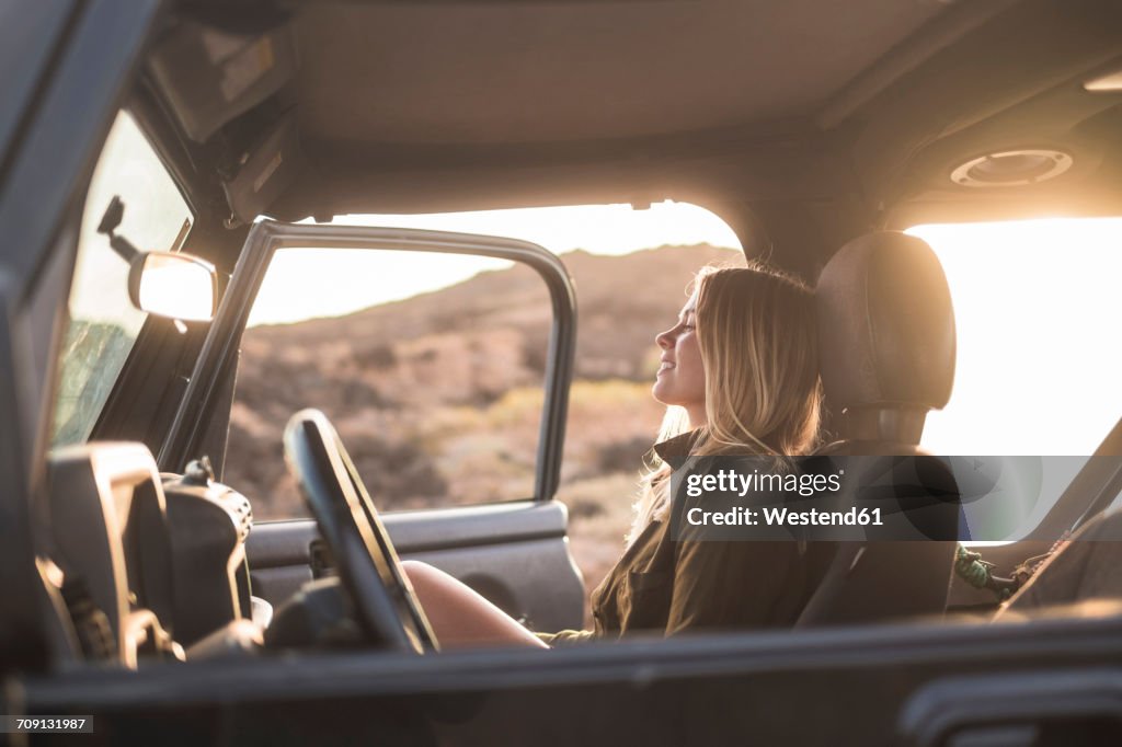 Woman sitting in car at sunset