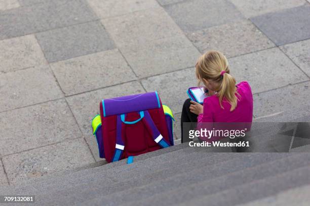 back view of little girl with school bag sitting on stairs doing homework - summer school stock pictures, royalty-free photos & images