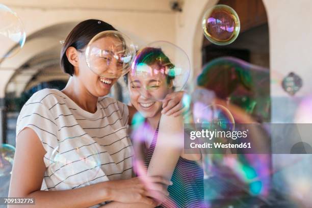 two young women playing with soap bubbles - chinese friends stock-fotos und bilder