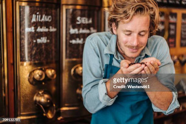coffee roaster in his shop smelling at coffee beans - indulgence foto e immagini stock
