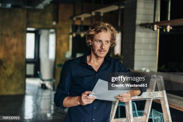 man leaning on ladder in unfinished room - the project portraits stock-fotos und bilder