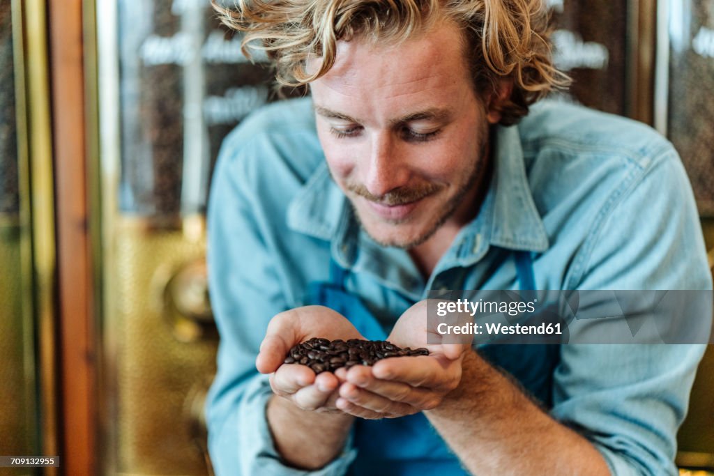 Coffee roaster in his shop smelling at coffee beans
