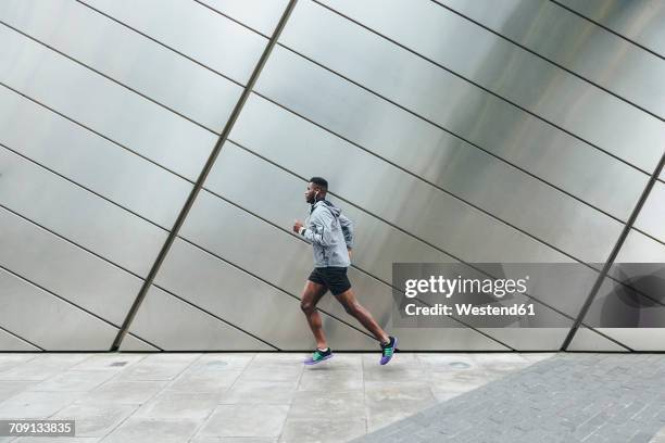 young man running along building front - man running city stock pictures, royalty-free photos & images