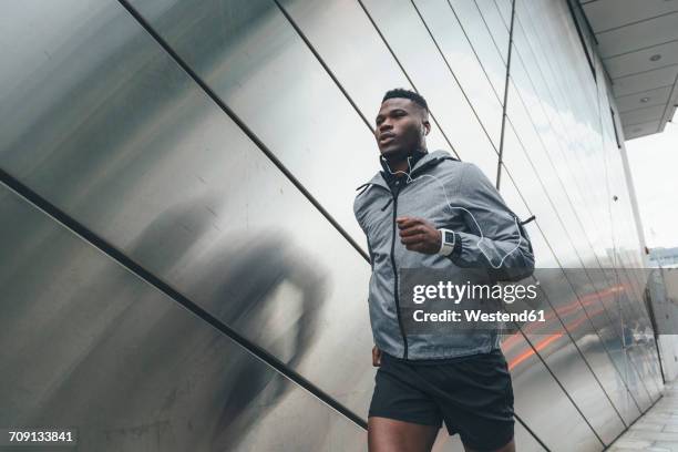 young man running along building front - center athlete stock pictures, royalty-free photos & images