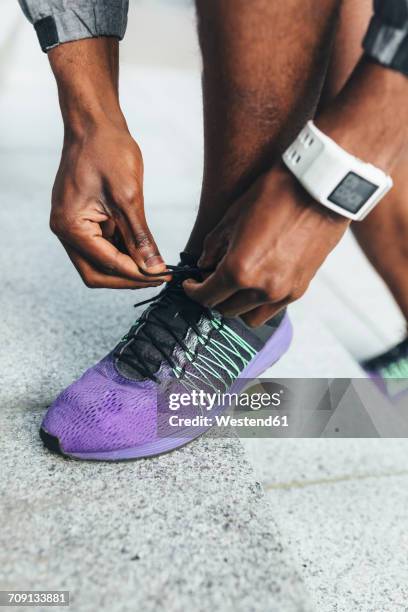 close-up of athlete wearing smartwatch tying shoes - black men feet stock-fotos und bilder