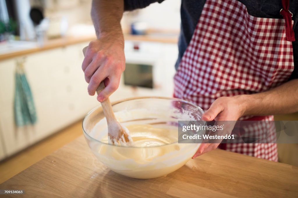 Man standing in kitchen, preparing cake dough