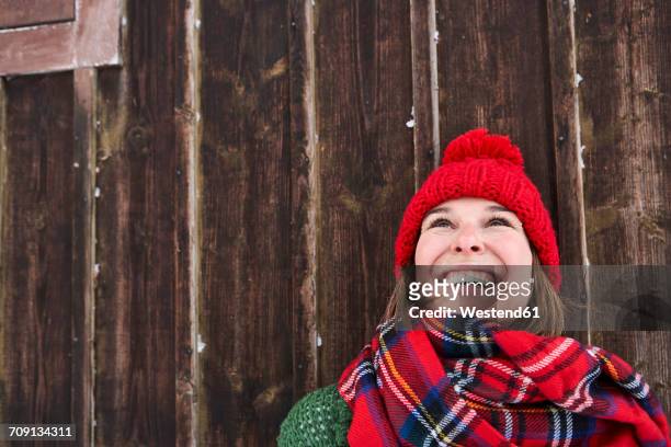 portrait of smiling woman wearing red bobble hat in winter looking up - bobble hat stock pictures, royalty-free photos & images