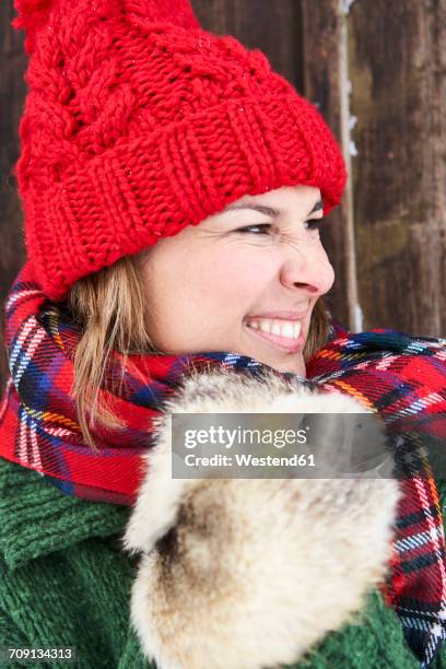 portrait of woman wearing red bobble hat and fur gloves in winter - red scarf stock-fotos und bilder