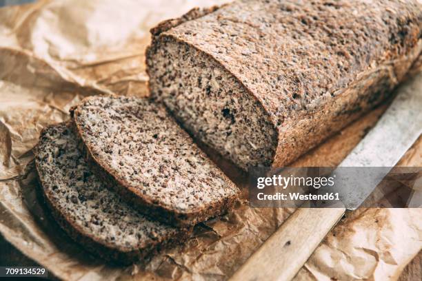 home-baked wholemeal glutenfree bread and bread knife on brown paper - semilla-de-lino fotografías e imágenes de stock