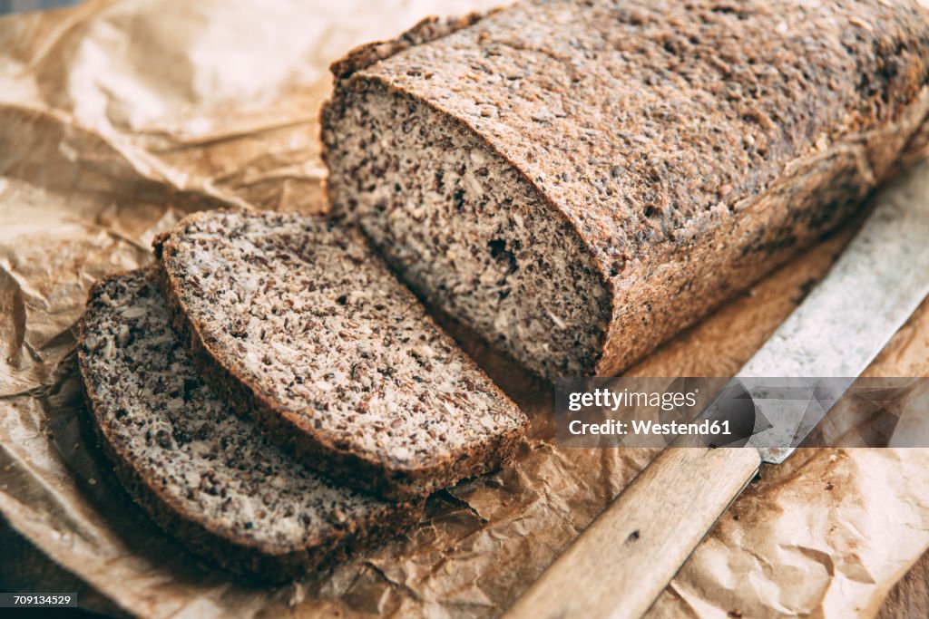 Home-baked wholemeal glutenfree bread and bread knife on brown paper