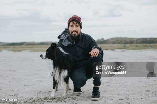netherlands, schiermonnikoog, man with border collie on the beach - schiermonnikoog stockfoto's en -beelden