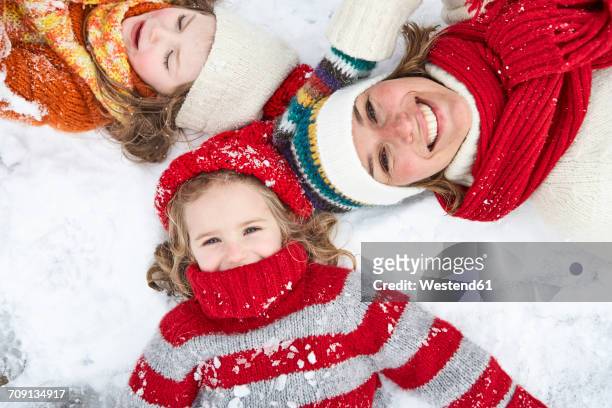 mother and daughters having fun in winter - family snow stock-fotos und bilder