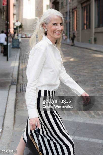 usa, brooklyn, portrait of smiling mature woman crossing the street - striped blouse stock pictures, royalty-free photos & images