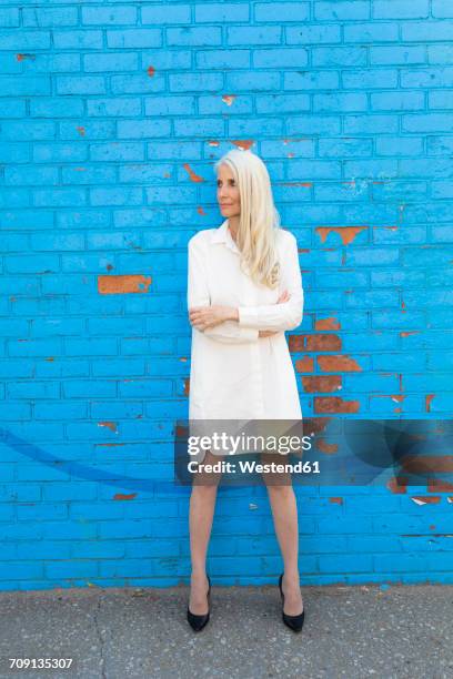 mature woman wearing white dress standing in front of light blue wall - 密頭高跟鞋 個照片及圖片檔