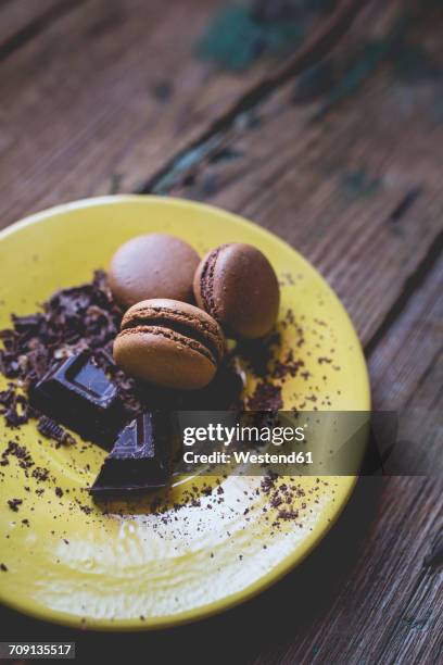 different macarons and chocolate shaving on yellow dish - chocolate chunks top view stock pictures, royalty-free photos & images