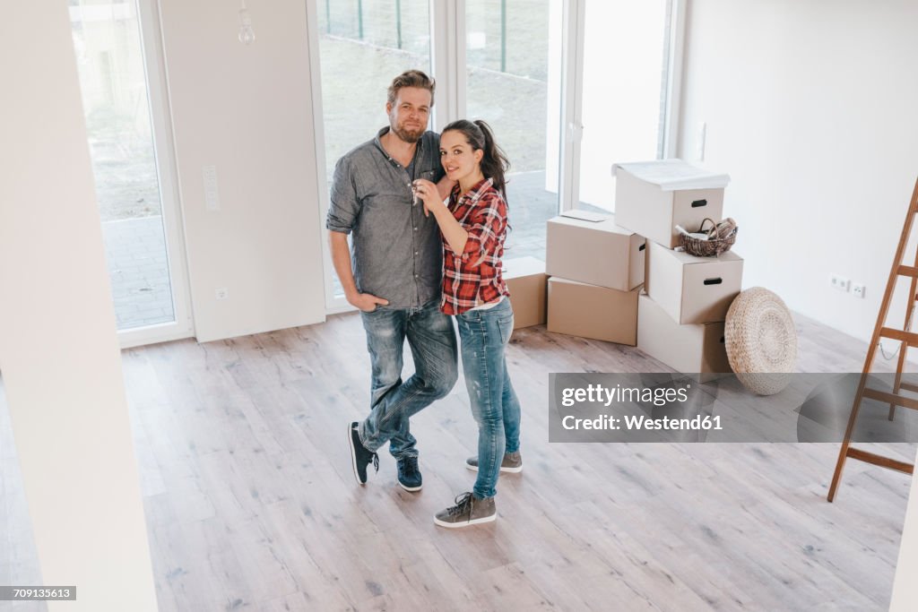 Couple moving house, woman holding keys of new home