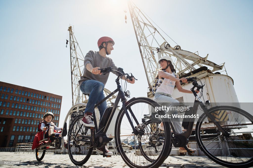 Germany, Hamburg, family riding e-bikes at the harbor