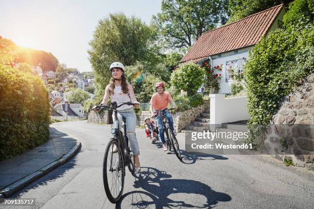 germany, hamburg, blankenese, family riding e-bikes - family riding bikes with helmets stock pictures, royalty-free photos & images
