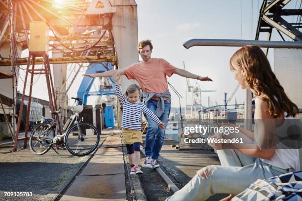 germany, hamburg, father and daughter balancing on rail at the harbor - bicycle daughter stock-fotos und bilder