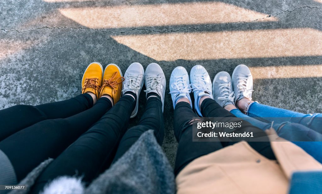 Legs of four friends standing side by side