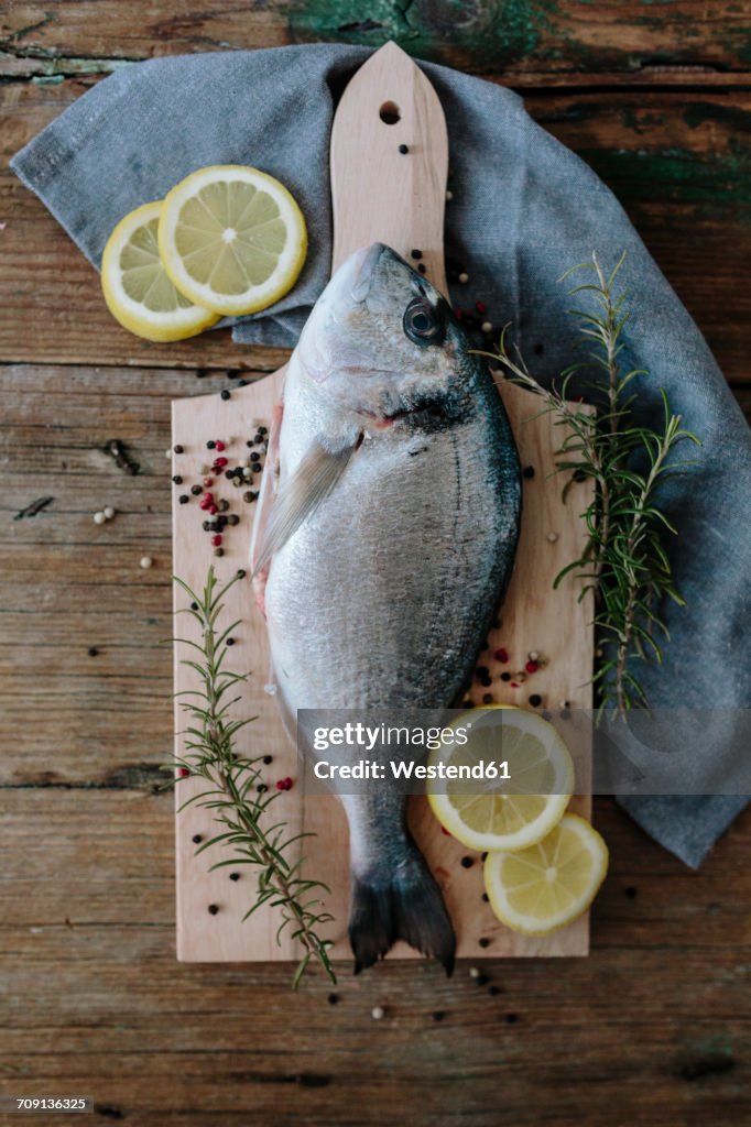 Sea Bream on a wooden board with pepper and rosemary