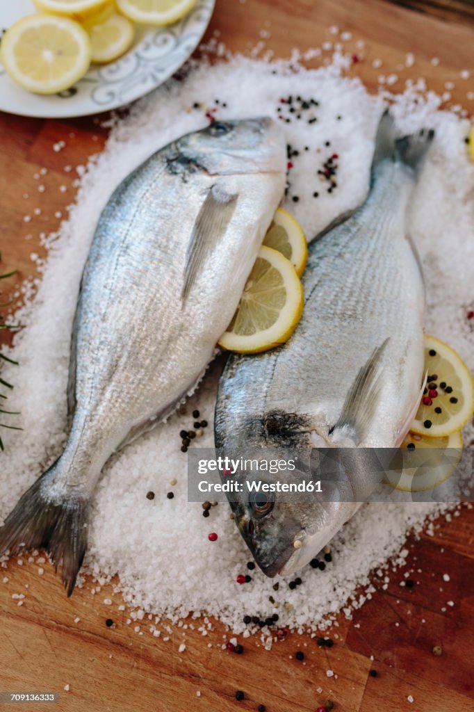 Sea Breams on a wooden board surrounded by salt grains