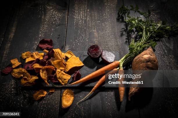 vegetable chips made of carrots, sweet patatoes and beetroot on dark wood - vegetable chips stock pictures, royalty-free photos & images