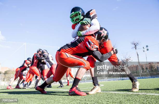 american football player being tackled by opponent player during a match - placcare foto e immagini stock