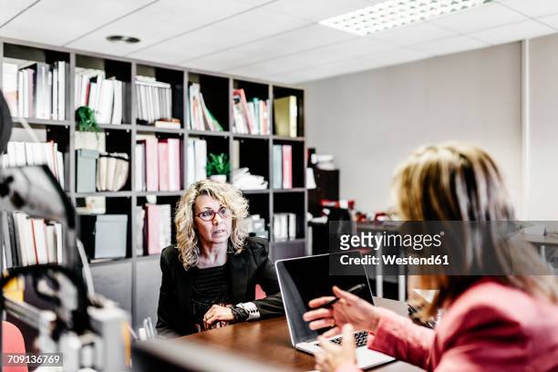 two businesswomen talking at desk in office - downsizing 2017 film stock-fotos und bilder