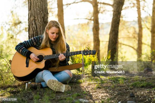 young woman playing guitar in nature - cantautor fotografías e imágenes de stock
