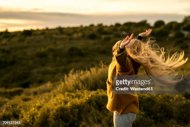 young woman standing in nature raising her arms - sin limites fotografías e imágenes de stock