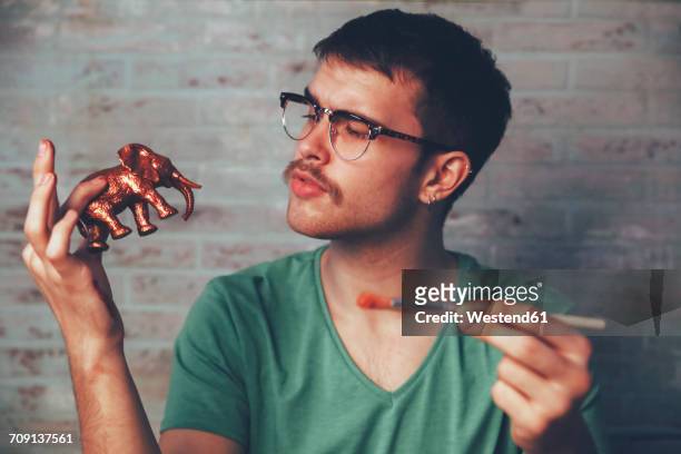 young man painting plastic elephant figure with copper paint - stereotypical stock pictures, royalty-free photos & images