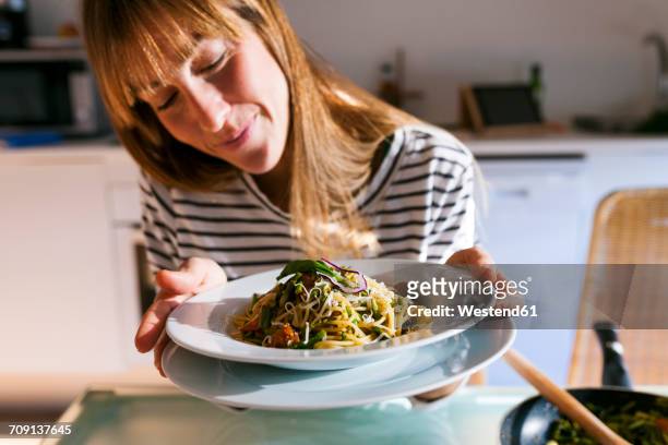 young woman serving vegan pasta dish - speisen und getränke stock-fotos und bilder