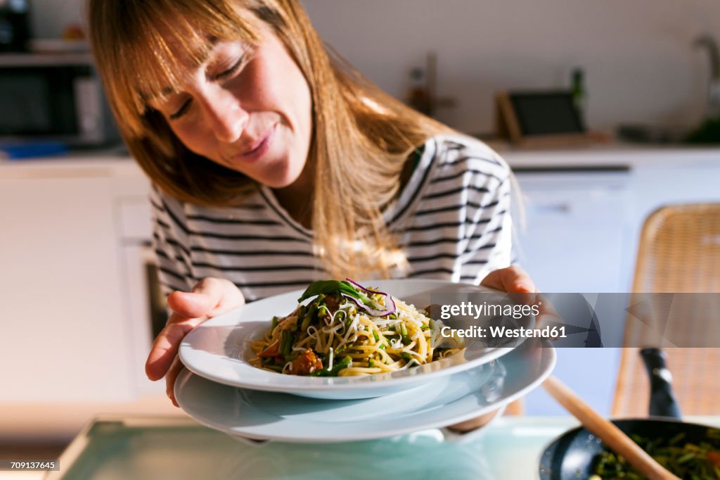 Young woman serving vegan pasta dish