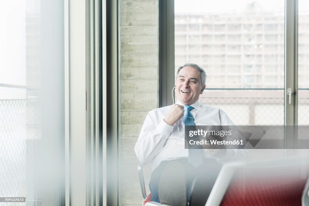 Senior manager in office sitting on chairs with feet up talking on the phone