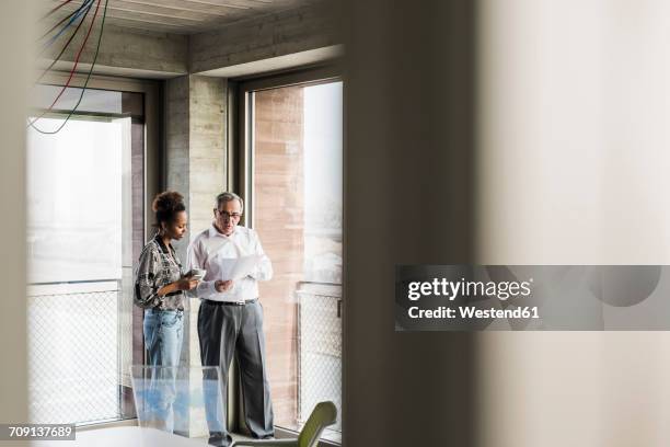 senior manager discussing documents with young coworker - werk in uitvoering stockfoto's en -beelden