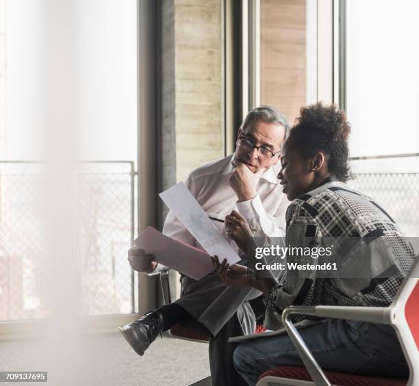 senior manager discussing documents with young coworker - global business leader stock pictures, royalty-free photos & images