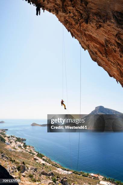 greece, kalymnos, climber abseiling in rock wall - freiklettern stock-fotos und bilder