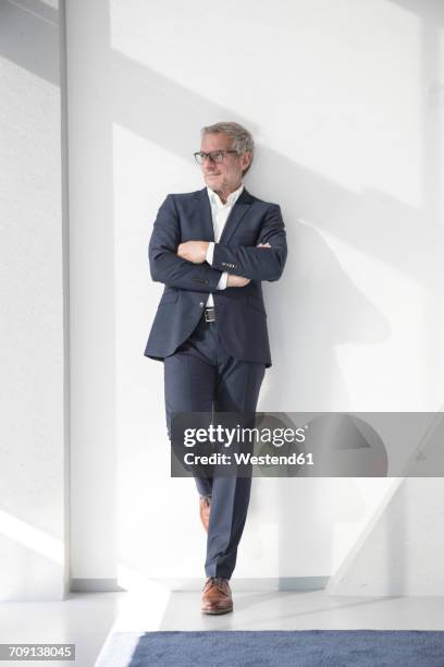 confident businessman leaning against a wall - leaning ストックフォトと画像