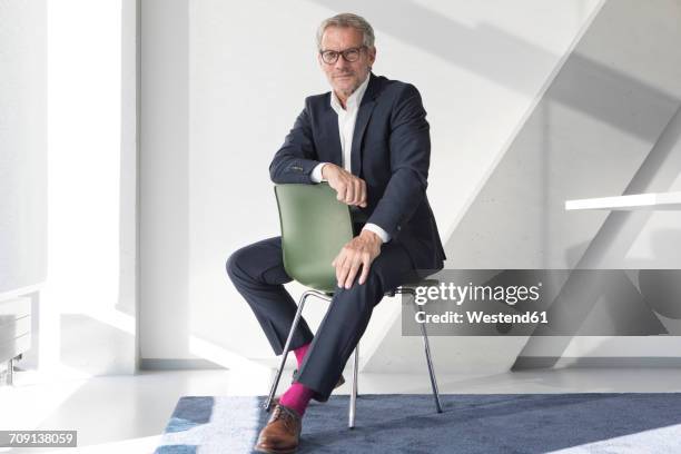 confident businessman sitting on chair - businessman sitting in chair stock-fotos und bilder