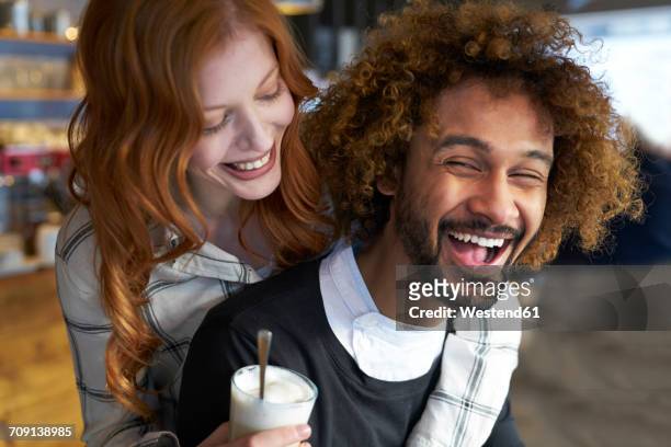 happy young man carrying girlfriend piggyback - coffee happy stockfoto's en -beelden