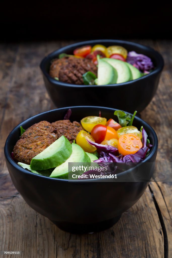 Lunch bowls of leaf salad, red cabbage, avocado, tomatoes and quinoa fritters